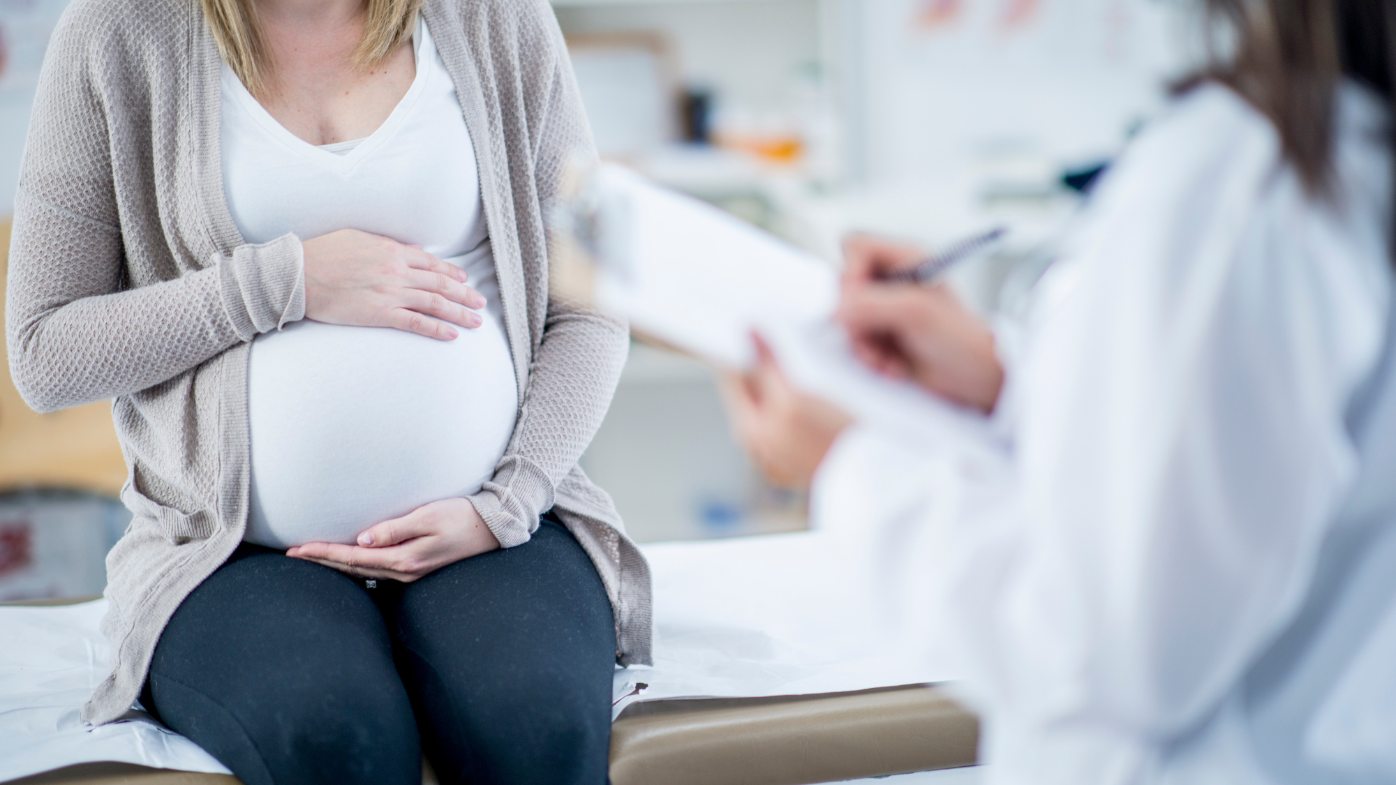 Pregnant woman holding belly at doctor's appointment